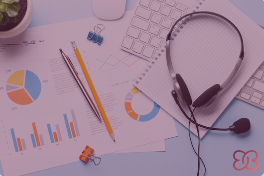 Draufsicht auf organisierte Arbeitsmaterialien mit Diagrammen, Notizblock und Headset